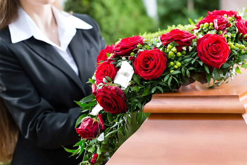 Arrangement floral de roses rouges posé sur un cercueil en bois.